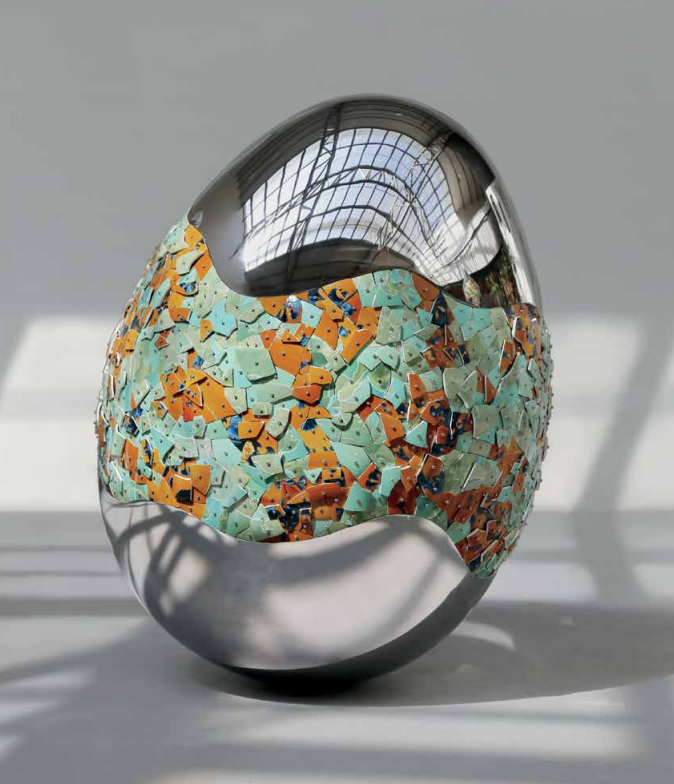 Egg-shaped sculpture blending chrome and brown and turquoise ceramic tiles 