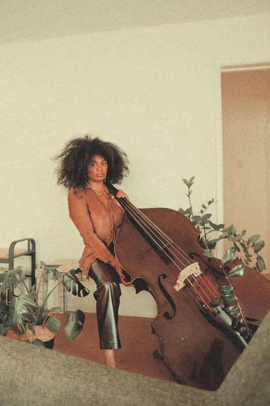 Young Black woman seated with very large upright bass