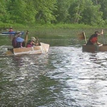 People racing cardboard boats in the water