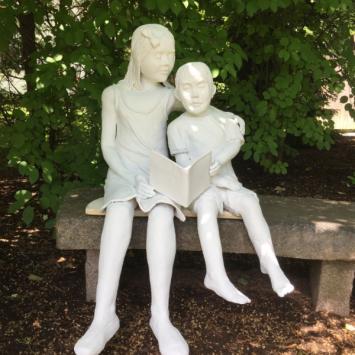 White sculpture of two children sitting and reading